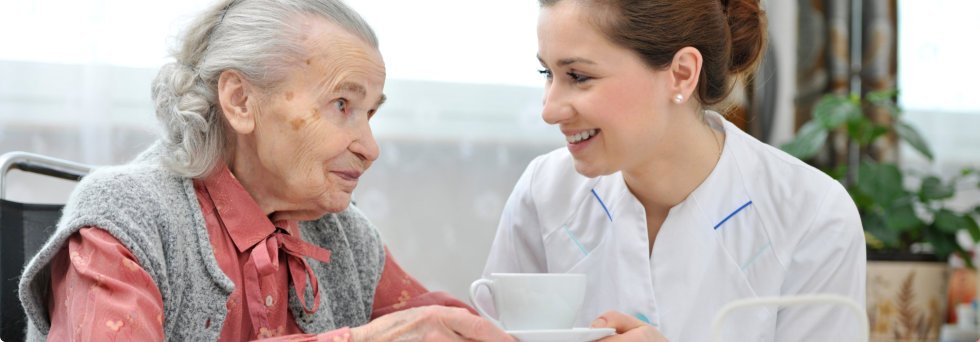 Caregiver serving a cup of tea to patient